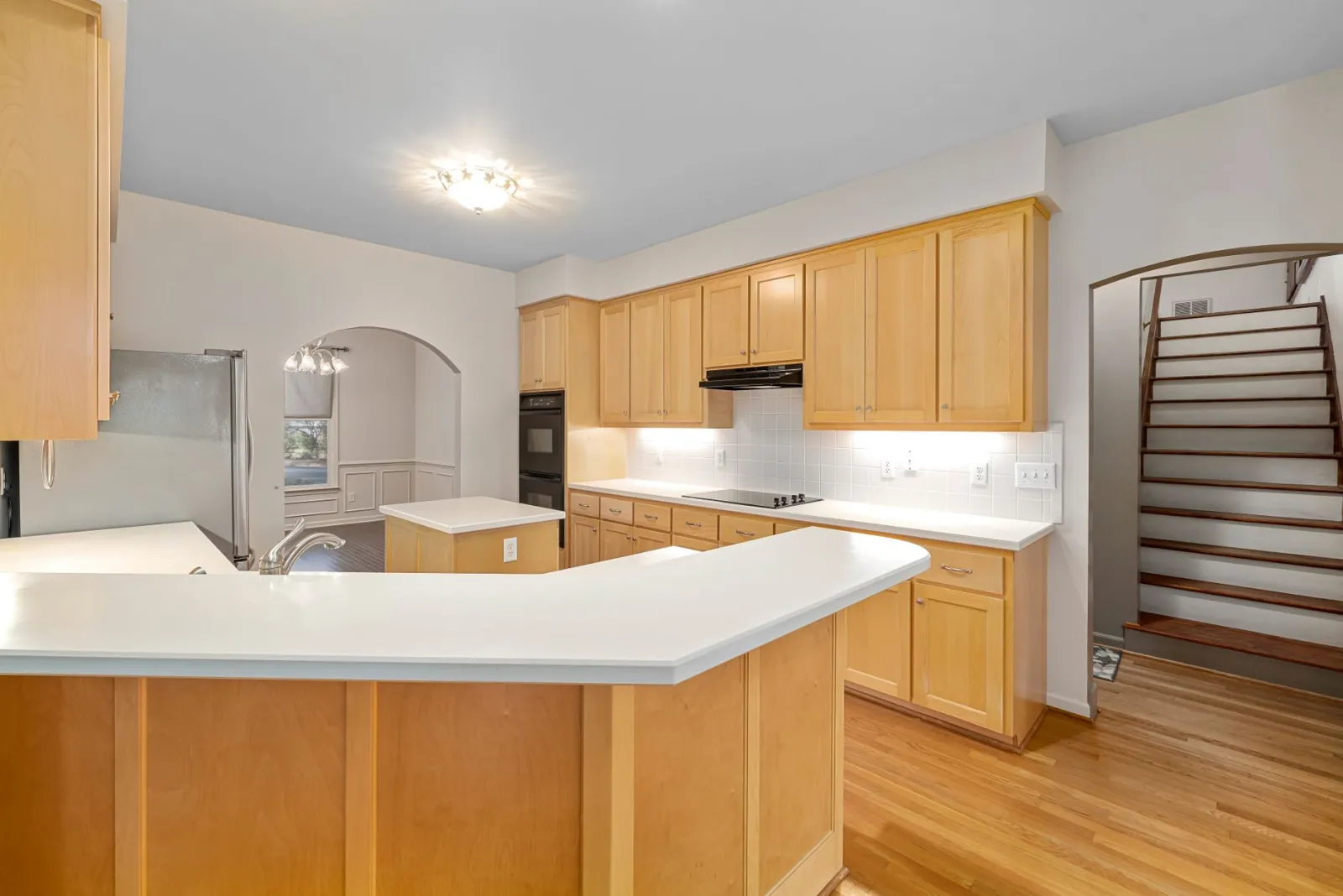 Bright modern kitchen featuring wooden cabinets, white countertops, and a central island.